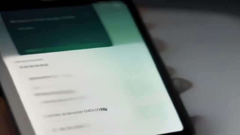Macro close-up of iPhone display showing iOS 27 App Permission Tracker settings with on-device AI toggles and permission tokens