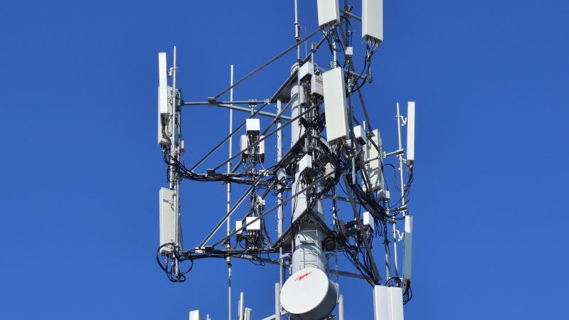 Close-up engineering view of telecommunications Massive MIMO antenna array hardware on cellular base station with microwave dish and high-speed feeder lines